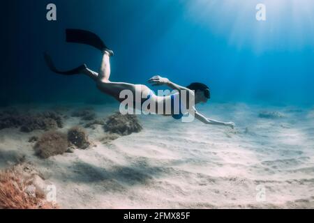 Belle femme de frediver avec nageoires plongée sous l'eau profonde dans la mer. Banque D'Images