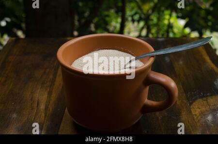 levure dans le grain, sécher dans une tasse d'argile, avec une cuillère en métal à l'intérieur sur le bois, avec un fond naturel pour faire du pain maison Banque D'Images