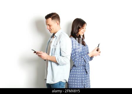 Jeune homme et jeune femme américain tenant la main sur le téléphone portable. Modèle homme et femme Jean bleu robe-chemise à carreaux. Concept Nomofobia. Smartphone zombi Banque D'Images