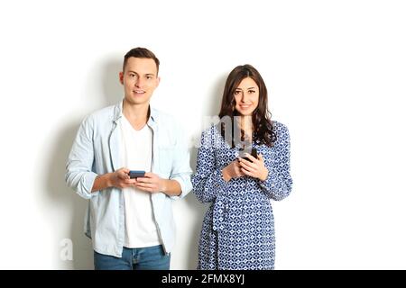 Jeune homme et jeune femme américain tenant la main sur le téléphone portable. Modèle homme et femme Jean bleu robe-chemise à carreaux. Concept Nomofobia. Smartp Hone zomb Banque D'Images