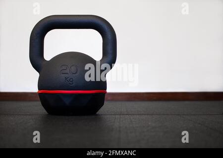 Gros plan de 20Kg de kettlebell noir isolé sur le sol à la salle de gym. Matériel de musculation et de fitness sur fond blanc avec espace vide pour le texte Banque D'Images