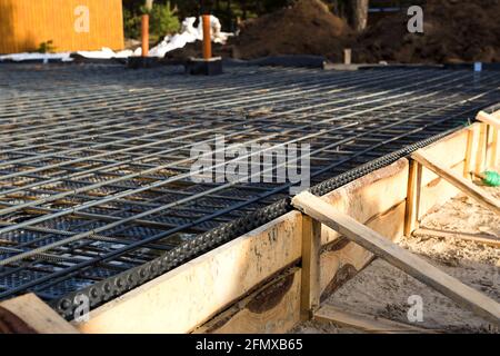 Les ferrures sur une coffrage en bois avec des tuyaux coudés sont la base pour verser la fondation de la maison avec une dalle de béton. Construction de chalet Banque D'Images