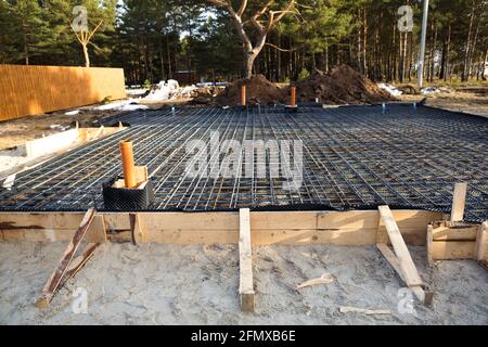 Les ferrures sur une coffrage en bois avec des tuyaux coudés sont la base pour verser la fondation de la maison avec une dalle de béton. Construction de chalet Banque D'Images