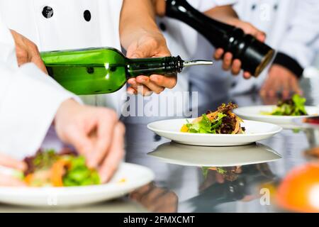 Chef de l'Indonésie en Asie avec d'autres cuisiniers dans un restaurant ou un hôtel restaurant la cuisine, plaque ou plat de finition Banque D'Images