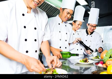 Chef de l'Indonésie en Asie avec d'autres cuisiniers dans un restaurant ou un hôtel restaurant la cuisine, plaque ou plat de finition Banque D'Images