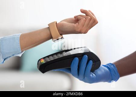 Black man tenant le client de la machine de point de vente payant avec la montre intelligente Banque D'Images