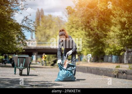 une femme volontaire nettoie le parc et l'arbre de la litière en plastique avec sac poubelle Banque D'Images