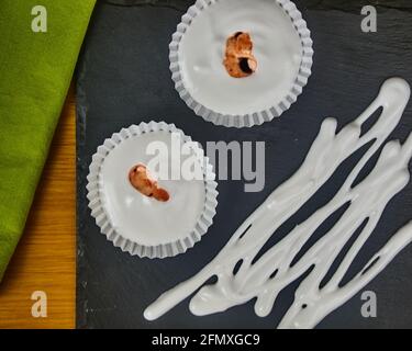 Plusieurs meringues de dessert français cru avec sauce aux fraises et garniture au sirop de meringue, ornées d'une serviette sur un tableau d'ardoise noire. Haut et gros plan Banque D'Images