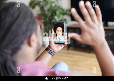 Homme afro-américain utilisant un smartphone pour la connexion vidéo avec une collègue, homme noir tenant le téléphone avec la charmante femme biracial sur l'écran, a appel vidéo avec une petite amie Banque D'Images