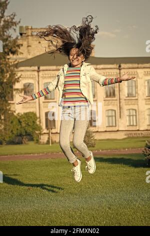 joyeux enfant sautant haut. sens de la liberté. bonheur d'enfance. petite fille avec des cheveux bouclés saut à l'extérieur. vacances de printemps enfin. fête d'enfant Banque D'Images