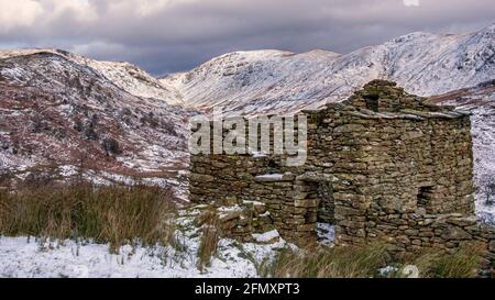 Les vestiges d'une ancienne grange en pierre du lac Quartier près du sommet de Kirkstone Pass avec la neige Pentes couvertes de Thornthwaite Crag dans la dista Banque D'Images