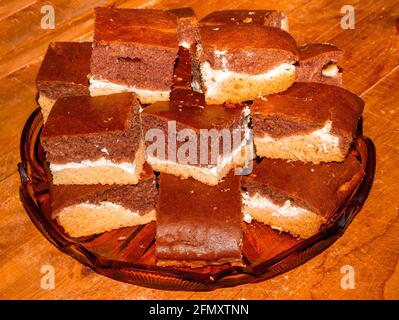 Trois brownies de couleur avec du fromage cottage sucré au milieu, empilées en plusieurs couches sur un plateau en verre Banque D'Images