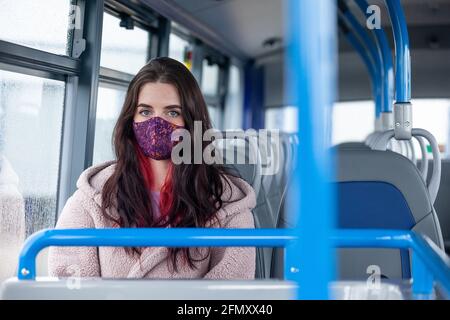 Une jeune femme assise dans un bus regardant vers la caméra Banque D'Images