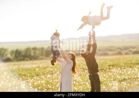 promenades en famille dans la nature. Maman et papa lancent leurs enfants Banque D'Images