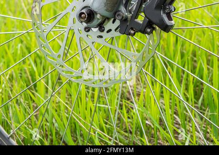 Partie du disque de frein d'un VTT sur fond d'herbe verte. Concept de style de vie sain Banque D'Images