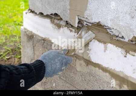 Travaux de maçonnerie. Main de travail dans un gant bleu avec une truelle. Banque D'Images