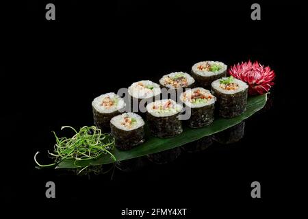 Rouleaux unagi maki sur feuille de bambou sur fond noir Banque D'Images