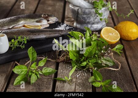 Gros plan de basilic frais sur une table en bois avec de la truite crue et citron Banque D'Images