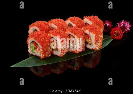 Rouleaux de Californie avec du saumon et du tobiko sur une feuille de bambou arrière-plan noir Banque D'Images