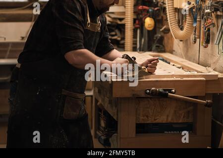 Homme charpentier utilisant la fraiseuse à main dans son atelier Banque D'Images