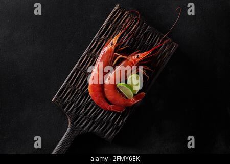 Vue de dessus de deux crevettes rouges royales avec citron vert planche en bois Banque D'Images