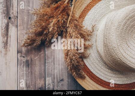 chapeau brun paille et beige et branches sèches de roseaux sur fond de bois. chapeau d'été à bord Banque D'Images