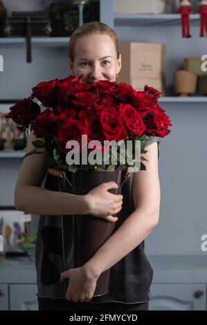 fille tenant un énorme bouquet de roses rouges en elle mains Banque D'Images