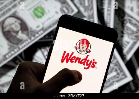 Chine. 21 avril 2021. Sur cette photo, le logo de la chaîne de restauration rapide américaine Wendy s'affiche sur un smartphone avec une devise en dollars américains (USD) en arrière-plan. Crédit: Budrul Chukrut/SOPA Images/ZUMA Wire/Alay Live News Banque D'Images