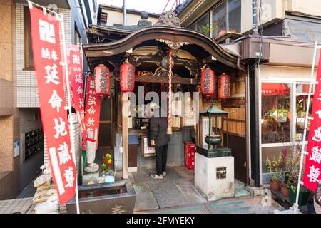 Tokyo, Japon - 9 janvier 2016 : un homme japonais ligace une bougie dans un petit sanctuaire de rue dans le quartier de Yanaka Ginza. C'est l'un des rares quartiers Banque D'Images