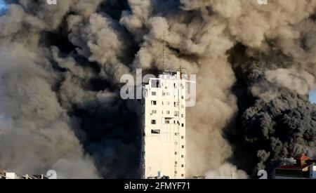 Gaza, Palestine. 12 mai 2021. La fumée s'élève dans une tour détruite par des frappes aériennes israéliennes dans le contexte d'une flambée de violences israélo-palestiniennes à Gaza CityIsrael a mené des centaines de frappes aériennes à Gaza mercredi et des militants palestiniens ont tiré plusieurs barrages-fusées à tel aviv et dans la ville de Beersheba, dans le sud de la région hostilités intenses en années. Crédit : SOPA Images Limited/Alamy Live News Banque D'Images