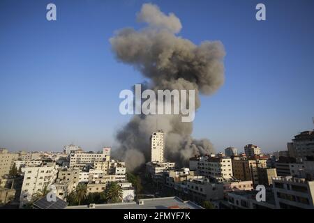 Gaza, Palestine. 12 mai 2021. La fumée s'élève dans une tour détruite par des frappes aériennes israéliennes dans le contexte d'une flambée de violences israélo-palestiniennes à Gaza CityIsrael a mené des centaines de frappes aériennes à Gaza mercredi et des militants palestiniens ont tiré plusieurs barrages-fusées à tel aviv et dans la ville de Beersheba, dans le sud de la région hostilités intenses en années. Crédit : SOPA Images Limited/Alamy Live News Banque D'Images