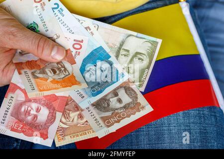 L'argent colombien, pesos, tenu dans la main avec le drapeau national. Concept économique Banque D'Images