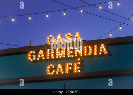 Panneau LED, lumière LED au néon avec la légende Casa Garmendia Cafe. Écriture centrale lumineuse et vive et enseigne orange au néon sur le toit du bâtiment Banque D'Images