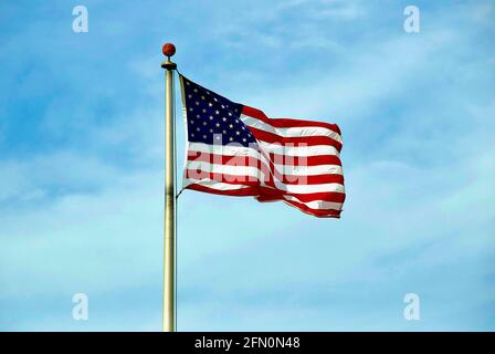 Le drapeau des États-Unis sur un mât vagues dans le vent lors d'un jour ensoleillé et de brise. Banque D'Images