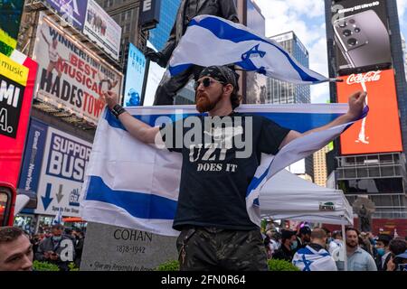 NEW YORK, NY - MAI 12 : un homme porte une chemise qui se lit « Uzi fait ça » et porte un drapeau alors que le Conseil israélo-américain (IAC) et d'autres groupes juifs américains se réunissent à Times Square en solidarité avec Israël le 12 mai 2021 à New York. Les rassemblements à travers l'Amérique montrent de la solidarité avec Israël et son peuple. Le président américain Joe Biden a déclaré aujourd'hui, le 12 mai, qu'Israël a le droit de se défendre, mais après avoir parlé avec le premier ministre Benjamin Netanyahou, il espère que les violents affrontements avec les Palestiniens se termineront rapidement. Crédit : Ron Adar/Alay Live News Banque D'Images