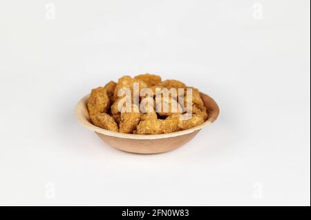 Croustilles de banane enrobées de jaggery ou sharkara varatti dans une areca bol à feuilles sur fond blanc Banque D'Images