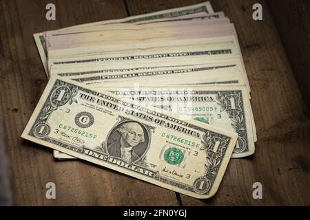 Un tas d'argent d'un billet américain avec le portrait du président Washington sur fond de table en bois. Espèces de billets en dollars, monnaie papier. Banque D'Images