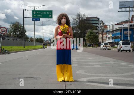 Bogota, Colombie. 12 mai 2021. Une femme se tient au milieu de la route avec une robe avec le drapeau colombien couleurs à l'envers et fleurs comme Bogota, La Colombie entre dans sa troisième semaine de manifestations antigouvernementales contre le président Ivan Duque Marquez et les morts qui s'résument à 40 cas de brutalité policière lors de la grève nationale, le 12 mai 2021. Crédit : long Visual Press/Alamy Live News Banque D'Images