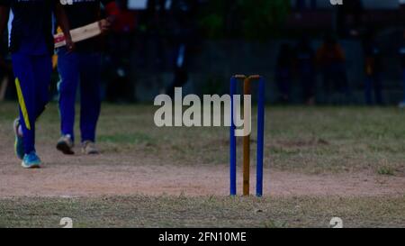 Match de cricket de softball dans le village, après le coucher du soleil dans l'obscurité. Terrain isolé et des portes en bois. Banque D'Images