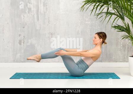 Femme faisant un équilibre de la variation Navasana yoga pose ou bateau pose pour se détendre et renforcer ses abdominaux, la colonne vertébrale et fléchisseurs de hanche dans une santé et des fitnes Banque D'Images