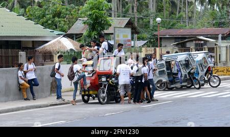 Élèves d'écoles à bord d'un tricycle dans la province de Sorsogon aux Philippines. Banque D'Images