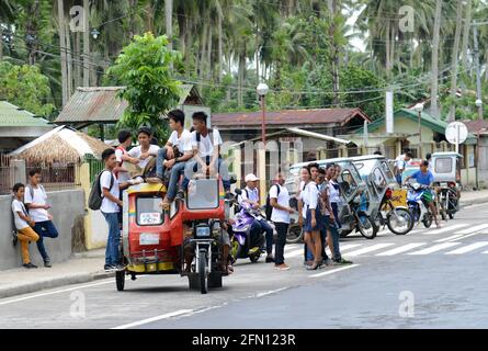 Élèves d'écoles à bord d'un tricycle dans la province de Sorsogon aux Philippines. Banque D'Images