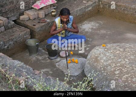 Jeune prêtre tribal adorant la statue de pierre de Lord Shiva dans un temple ouvert. TRIBU BAAIGA, Chiyapadar Baïga village d'Odisha, Inde Banque D'Images