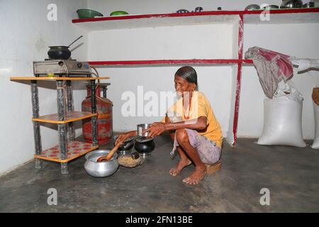 Une vieille femme tribale cuisinant de la nourriture dans la cuisine. LANJIA SAORA TRIBU. Puttasingh Village , Odisha, Inde Banque D'Images