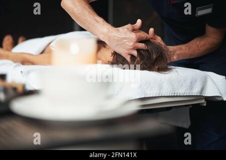 Une femme non reconnue sur la table de massage se détende la procédure sur la tête dans le salon de spa Banque D'Images