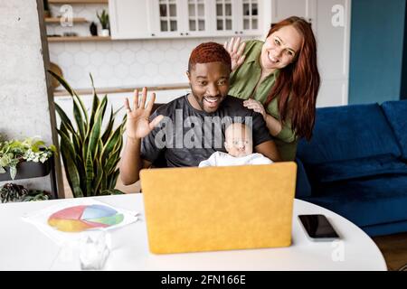 Heureux famille africaine mixte race ethnicité parents avec petit mignon petit enfant s'asseoir dans la salle de séjour rire en s'amusant, en saluant la famille, amis Banque D'Images