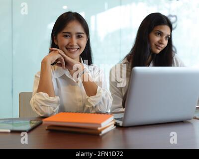 Portrait de deux étudiantes en bibliothèque leur mission avec des livres et un ordinateur portable Banque D'Images