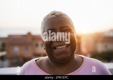 Bonne femme africaine senior souriant sur caméra en extérieur dans le Ville - Focus sur le visage Banque D'Images