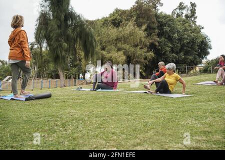 Des personnes multiraciales font des cours de yoga à l'extérieur dans le parc de la ville - Concentrez-vous sur le visage de la femme africaine Banque D'Images