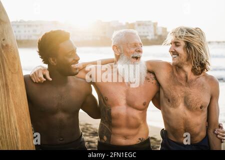 Amis surfeurs multigénérationnels s'amusant sur la plage après Session de surf - accent principal sur le visage de l'homme droit Banque D'Images